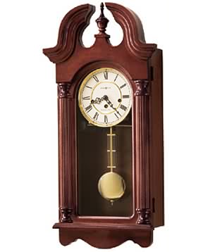 Howard Miller David 620-234 Keywound Wall Clock Features a swan neck pediment and turned finial.   Ivory dial features polished brass bezel, Roman numerals and decorative hands.   Polished brass pendulum features a decorative grid.   Finished in...